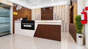 A reception desk with a sign reading 'TOWNHOUSE OYO-Serviced' in a modern lobby with wooden paneling and a marble floor. - Classic JR Royals (Golmuri)