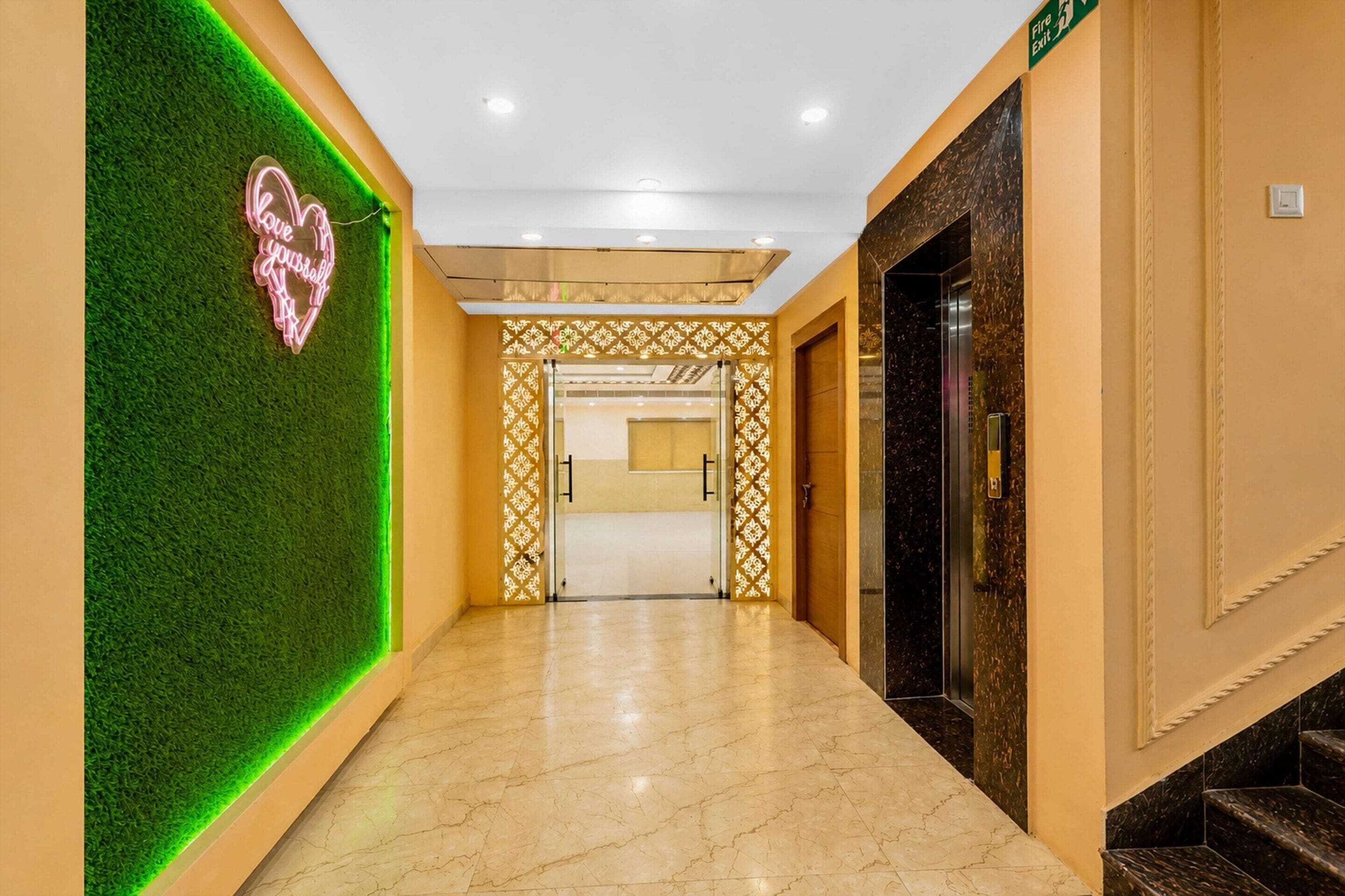 A hotel corridor with a green wall, a neon sign, and a marble floor.