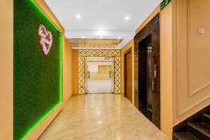 A hotel corridor with a green wall, a neon sign, and a marble floor. - Classic JR Royals (Golmuri)