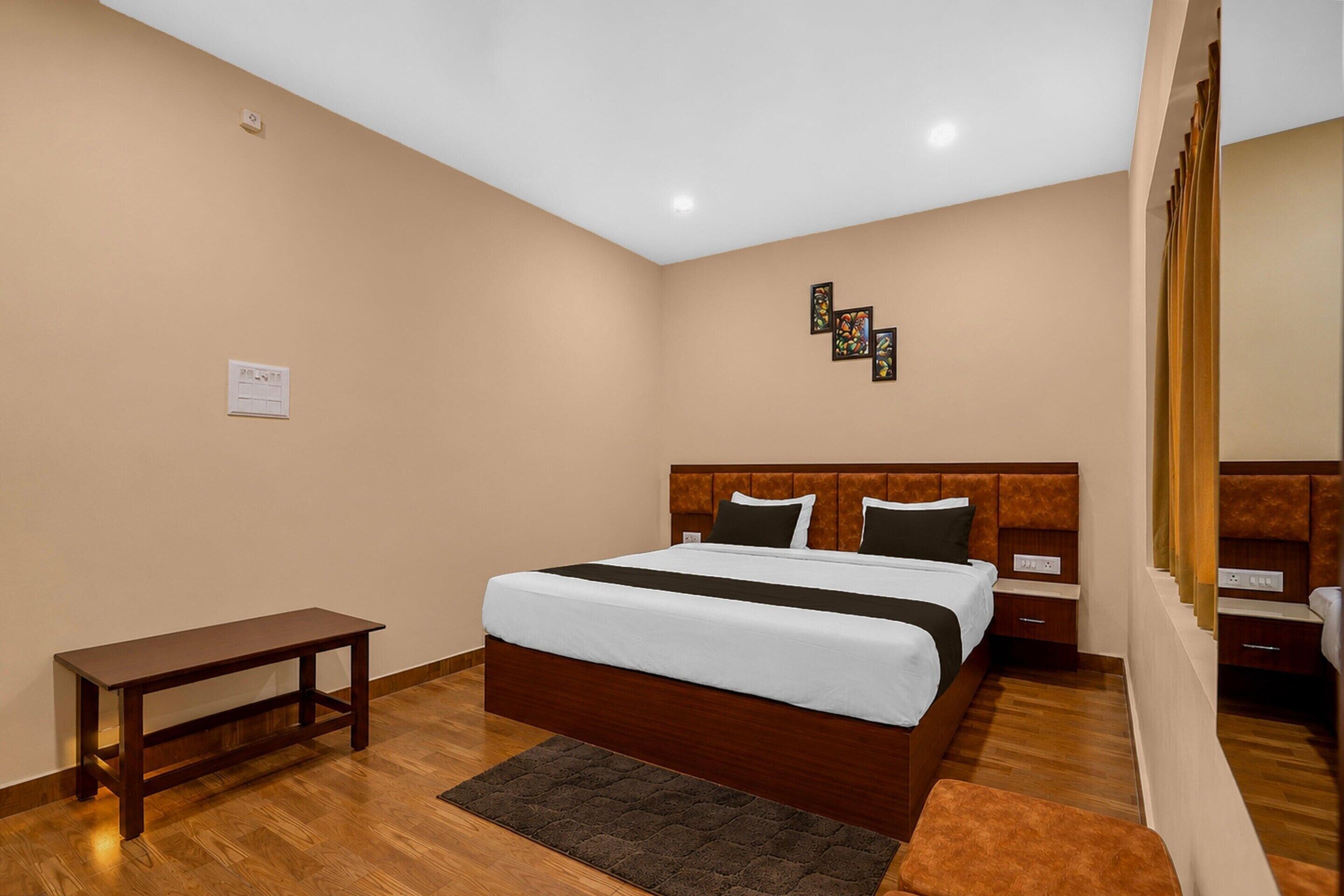 Una habitación de hotel con cama, mesitas de noche, un banco y una alfombra.