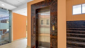 An elevator with a digital display, a marble wall, and a staircase. - Classic JR Royals (Golmuri)