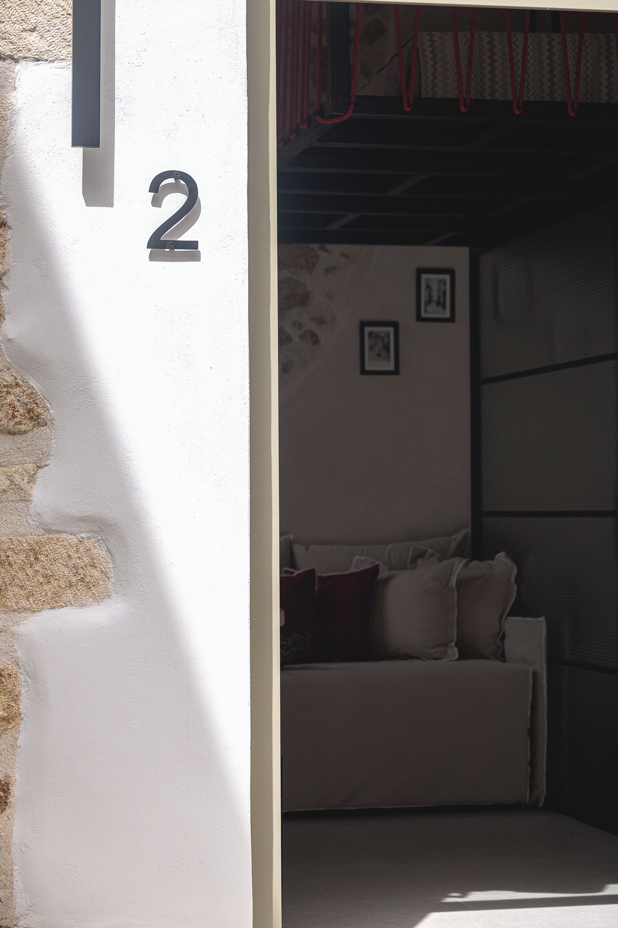 Une pièce avec un mur blanc, un panneau indiquant le numéro « 2 », un canapé et une fenêtre avec des stores.