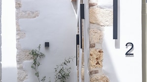 Pared de piedra con una planta en maceta y un cartel con el número 2.