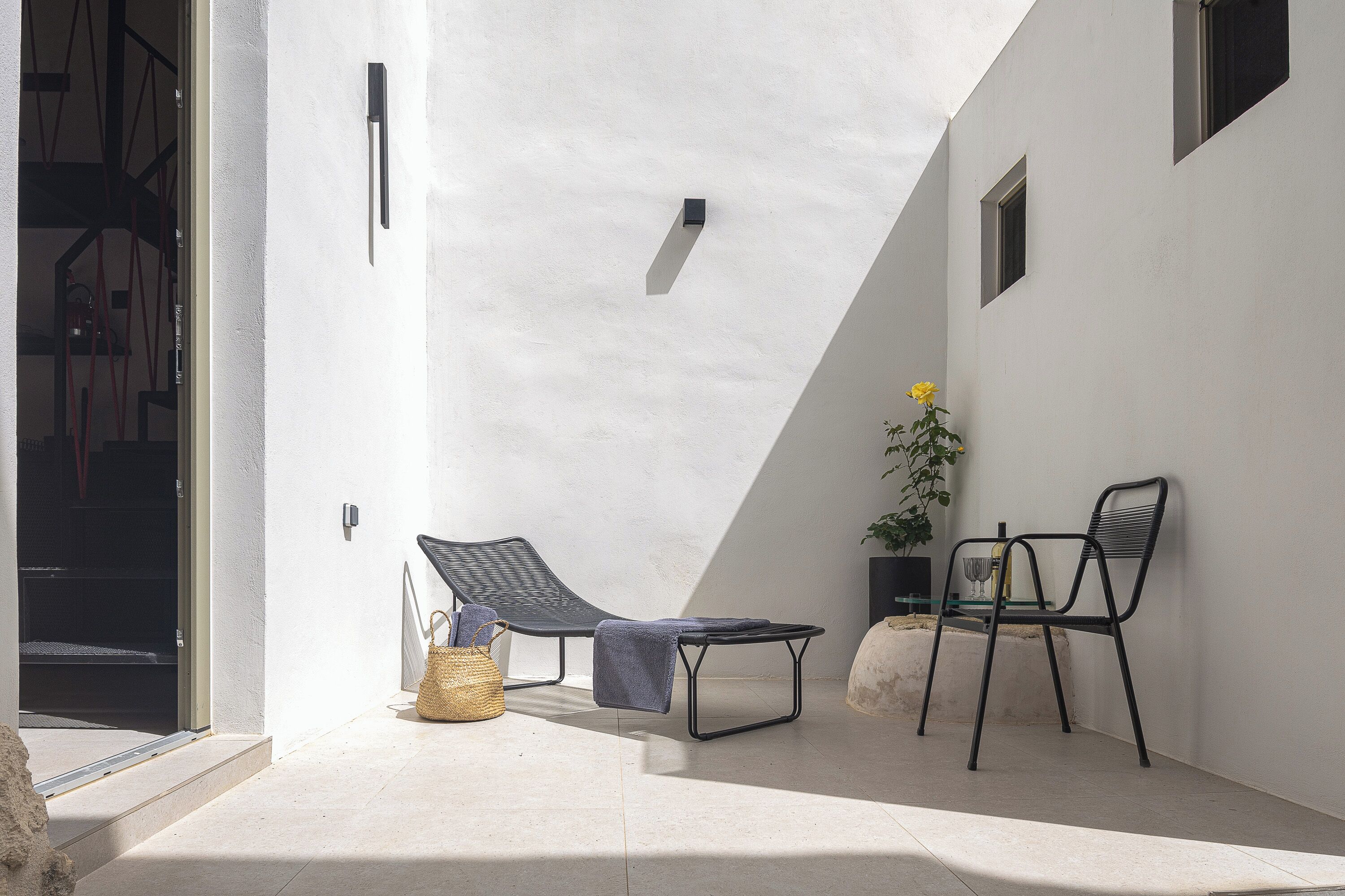 A modern outdoor seating area with a chaise lounge, a small table, and two chairs.