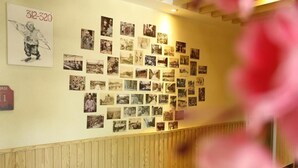 A wall with numerous photographs, a sign with '312-320', and a wooden paneling section. - Happy Dragon Alley Hotel-Forbidden City (Beijing)