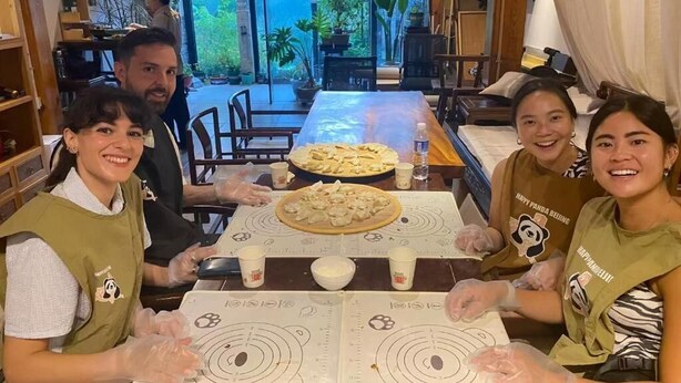 A dining area with a table set for four people, a pizza, and a menu. - Happy Dragon Alley Hotel-Forbidden City (Beijing)