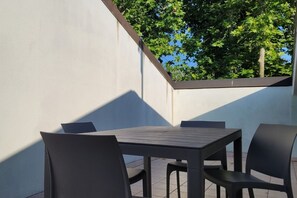 An outdoor patio with a table and chairs, a white wall, and a view of trees. - Location: in the central area, a few steps from the sea and all services.Description: very central four-room apartment on two floors connected by stairs.1st floor: large living room with sofa, table, kitchenette and dishwasher - bedroom with double bed - (Cesenatico)
