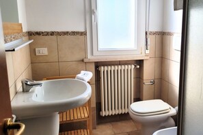 Et badeværelse med vask, toilet og vindue.