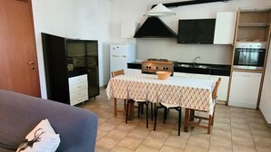 A compact kitchen with a dining table, a sofa, and a refrigerator. - Location: in the central area, a few steps from the sea and all services.Description: very central four-room apartment on two floors connected by stairs.1st floor: large living room with sofa, table, kitchenette and dishwasher - bedroom with double bed - (Cesenatico)