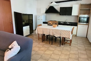 A compact kitchen with a dining table, a sofa, and a refrigerator. - Location: in the central area, a few steps from the sea and all services.Description: very central four-room apartment on two floors connected by stairs.1st floor: large living room with sofa, table, kitchenette and dishwasher - bedroom with double bed - (Cesenatico)