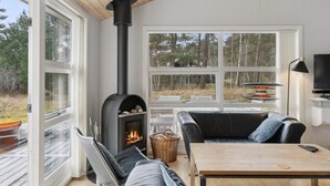 Ein modernes Wohnzimmer mit Kamin, einer Couch, einem Tisch und einem Fernseher.