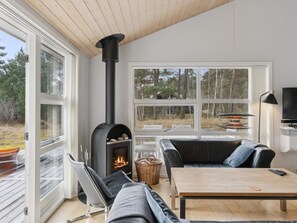 Ein modernes Wohnzimmer mit Kamin, einer Couch, einem Tisch und einem Fernseher.