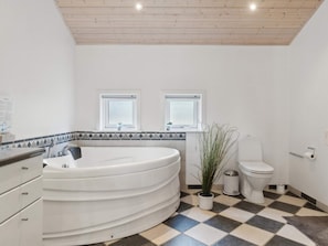 A modern bathroom with a freestanding bathtub, two windows, a toilet, and a potted plant. - 5 Star Holiday Home in Aakirkeby (Akirkeby)