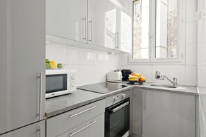 Eine moderne Küche mit weißen Schränken, einer Mikrowelle, einem Toaster, einer Spüle und einem Fenster.