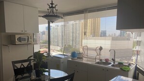 A compact kitchen with a microwave, a sink, and a dining area with chairs and a table. - 3-ROOM APARTMENT IN PUNTA PAITILLA WITH OPEN-PLAN KITCHEN, PARKING, WIFI, AND VISTASKY BUILDING (Panamá)
