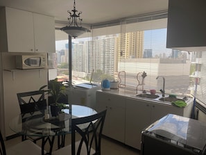 A compact kitchen with a microwave, a sink, and a dining area with chairs and a table.