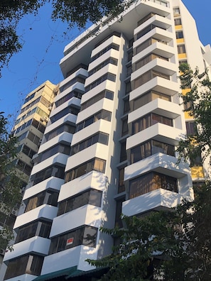 A multi-story building with a modern architectural design, featuring balconies and large windows.