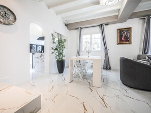 Een moderne woonkamer met een marmeren vloer, een eettafel, een bank en een potplant.