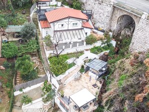 A white building with a red roof, a stone bridge, and a patio area with outdoor furniture. - BEAUSOLEIL FAMILY, WEDDING & EVENT VENUE IN FRANCE (Beausoleil)
