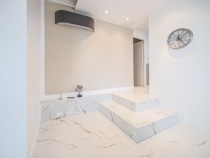 Une salle de bain moderne avec un sol en marbre, un grand miroir et une horloge murale.
