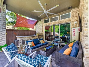 Un'area patio esterna con ventilatore a soffitto, barbecue e posti a sedere.