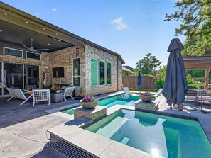 A swimming pool with a stone deck, lounge chairs, and a covered patio area. - Resort-style outdoor living paired with comfort, style, and relaxation (Atascocita)