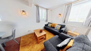 Ein modernes Wohnzimmer mit Sofa, Couchtisch, Sessel und kleinen Beistelltisch.