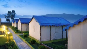 A row of tents with a paved walkway and greenery, set against a mountainous backdrop. - Sumitel Araku Mount View Camping Resort (Araku Valley)