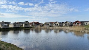 Una hilera de casas de un solo piso con un lago tranquilo al frente.