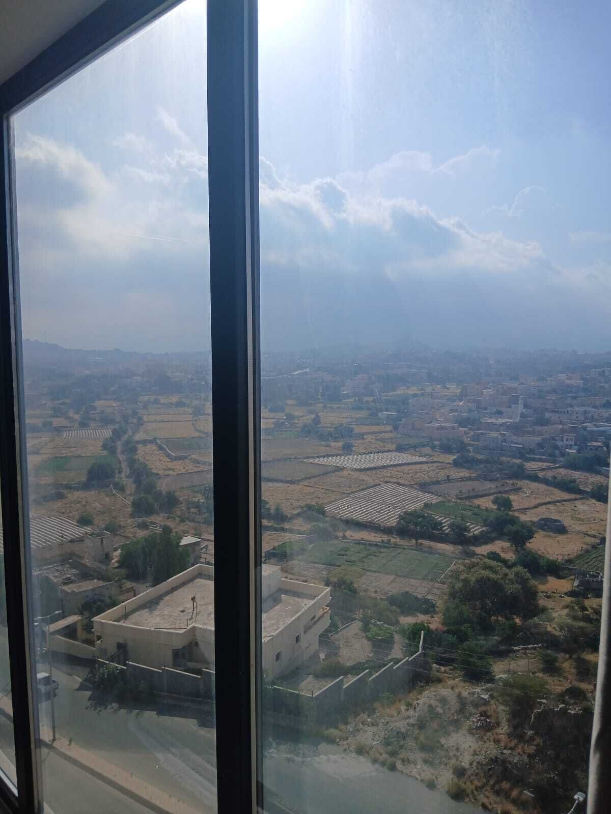 A view through a window of a cityscape with fields and buildings.