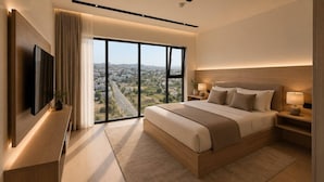 A modern bedroom with a large bed, a TV, a nightstand, and a view of a cityscape through large windows.
