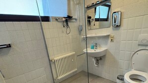 Un baño moderno con cabina de ducha de vidrio, un lavabo blanco y un inodoro.