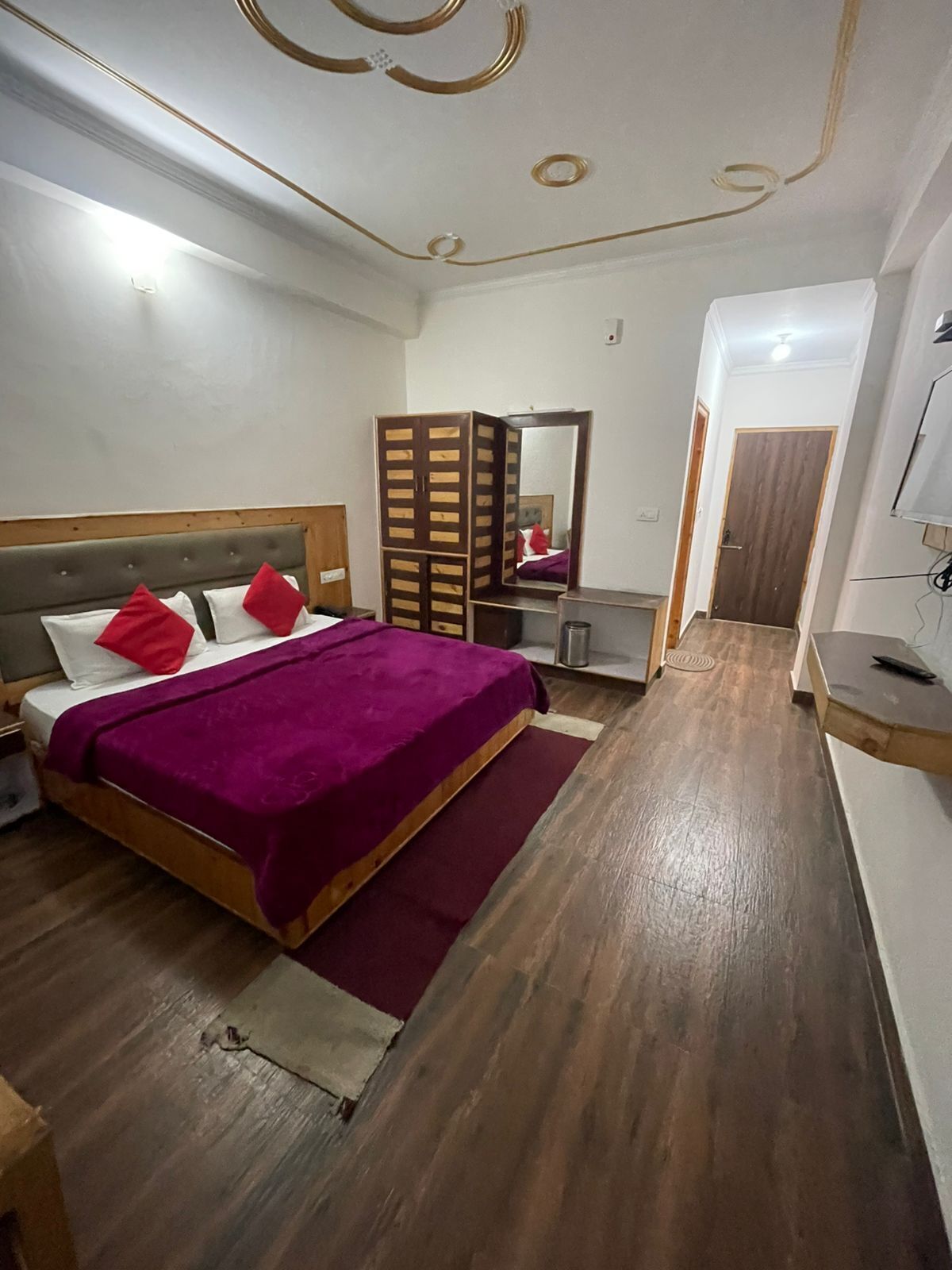A bedroom with a bed, a mirror, a wardrobe, and a desk.