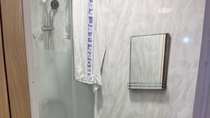 Ein Badezimmer mit Duschkabine, Toilette und Handtuchhalter.