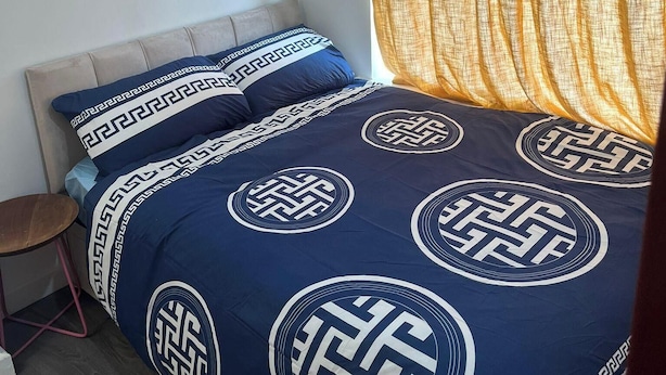 Ein Schlafzimmer mit Bett, Nachttisch, Stuhl und einem Fenster mit Vorhängen.