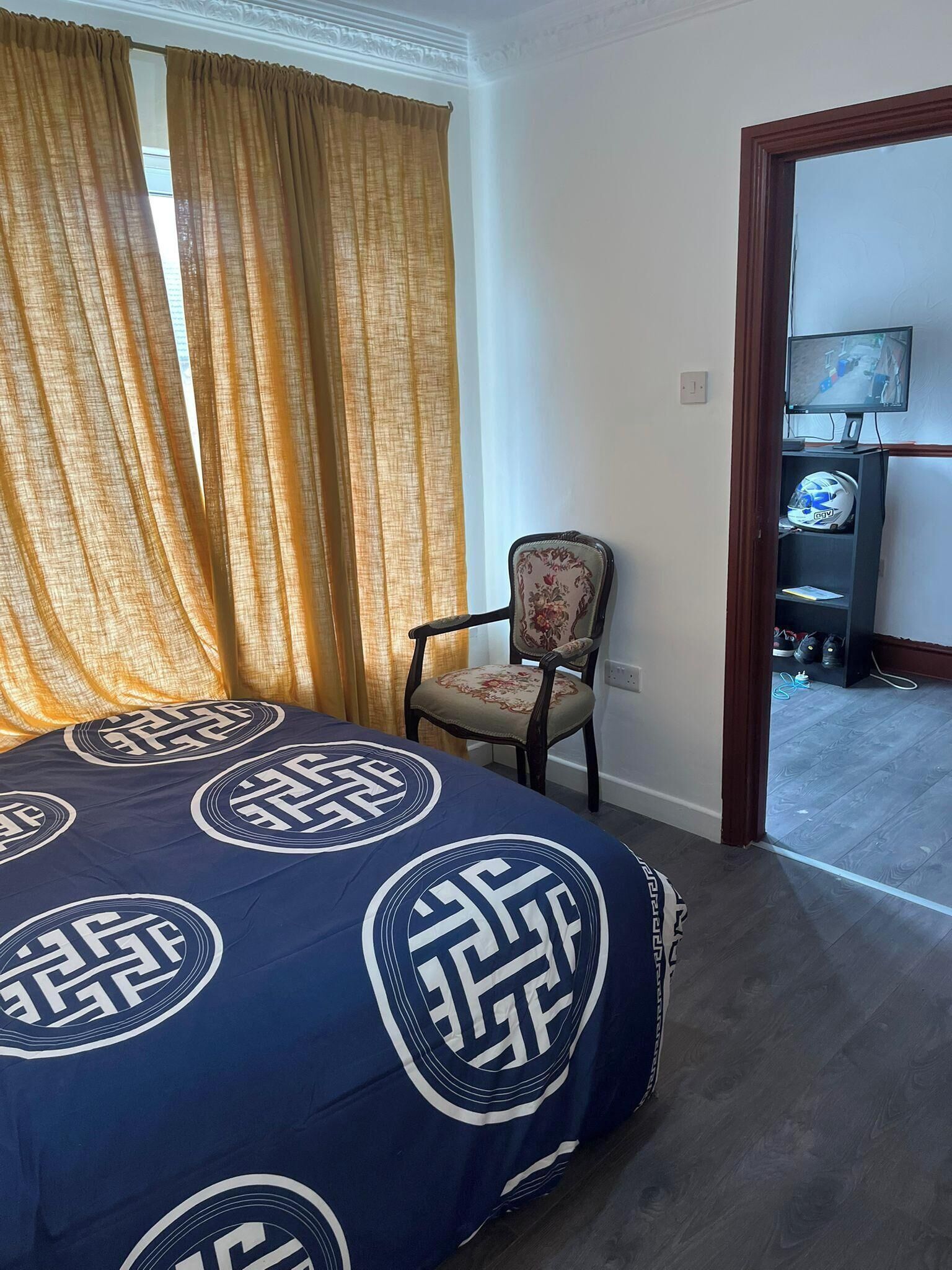 A hotel room with a bed, a chair, a television, and a door leading to a hallway.