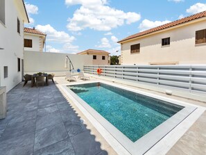 A rooftop swimming pool with a tiled deck, a table with chairs, and a railing. - Delina Coastal Villa Steps from Everything (Protaras)