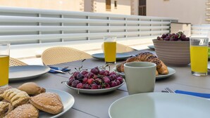 A table set with food and drinks, a bowl of grapes, and a croissant. - Delina Coastal Villa Steps from Everything (Protaras)