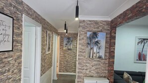 A hallway with stone walls, framed artwork, and a door leading to another room.