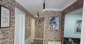 A hallway with stone walls, framed artwork, and a door leading to another room. - 🏡  Family-Friendly Comfortable Home. (Oakhurst)