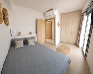 Ein Schlafzimmer mit einem Bett, einem Kleiderschrank, einem runden Teppich und einer Tür zu einem anderen Raum.