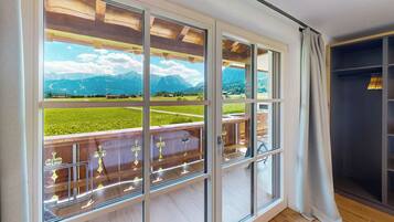 Ein Zimmer mit großen Fenstern, einem Holzbalkon und Bergblick.