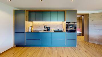 Eine moderne Küche mit blauen Schränken, Holzböden und eingebauten Geräten.