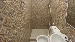 Ein Badezimmer mit gemusterten Fliesen, einer Toilette, einem Bidet und einem Waschbecken.