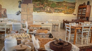 Un comedor con mesas dispuestas para el desayuno, que incluye bollería, tartas y una variedad de productos para el desayuno.