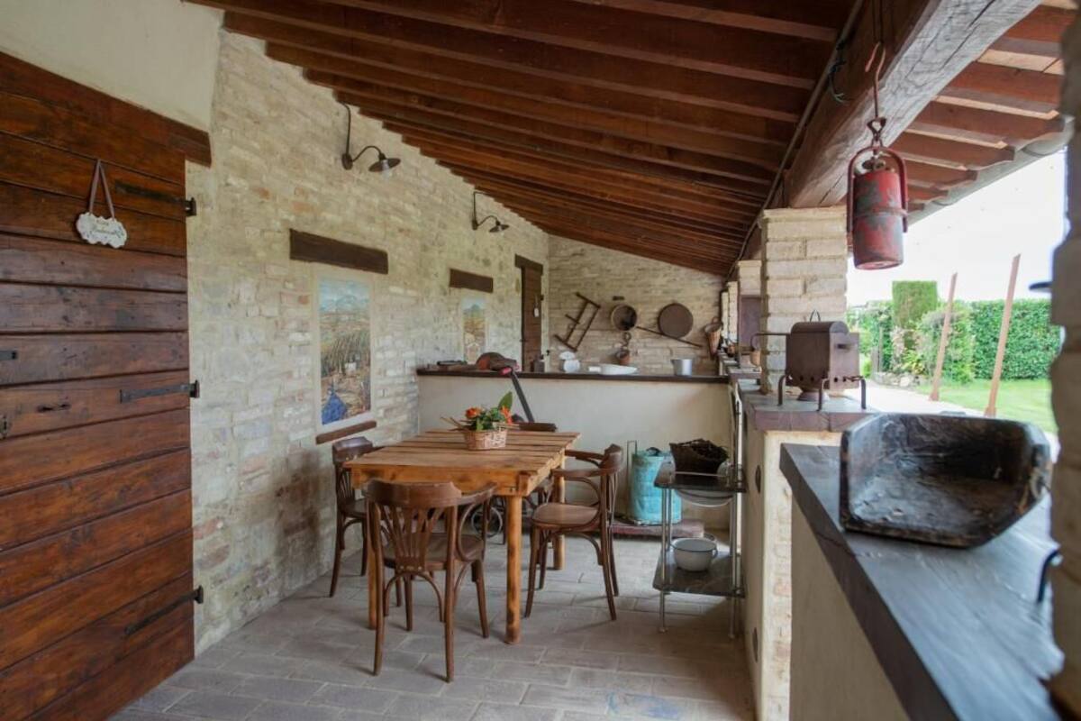 A rustic stone wall, wooden beams, a wooden table with chairs, and a hanging lantern.