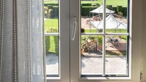 Una ventana con vista a un jardín y un paraguas blanco.