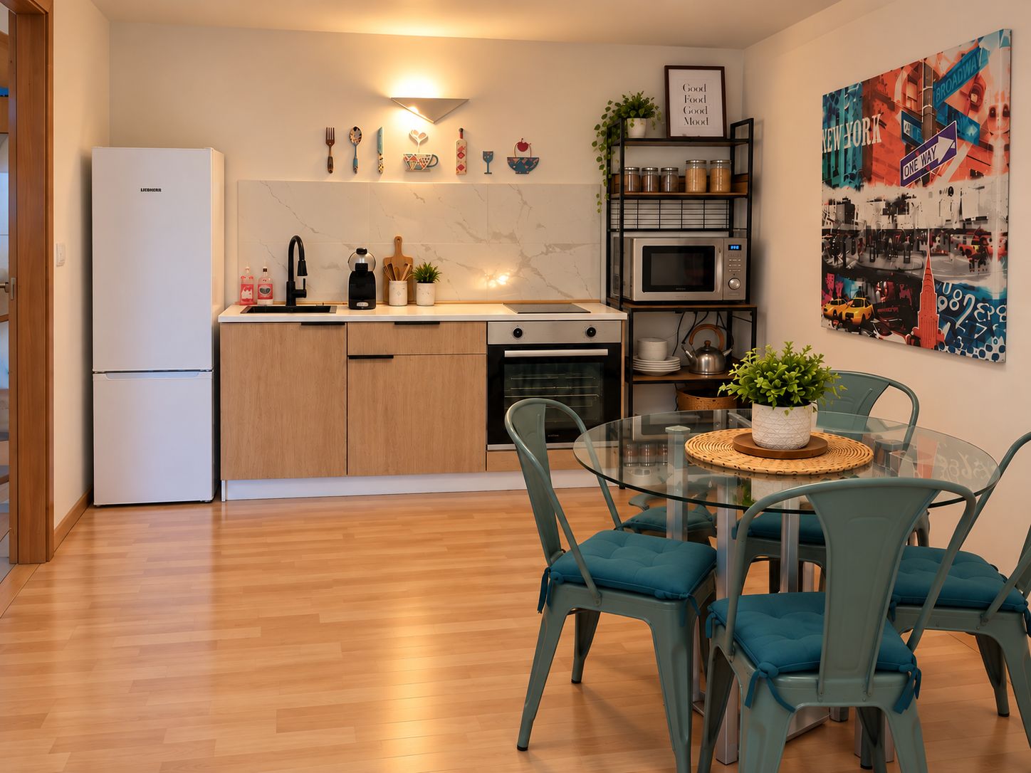 Una cocina moderna con refrigerador, estufa, microondas y una mesa de vidrio con sillas.