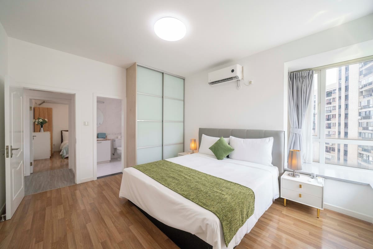Quarto de hotel com cama, mesa de cabeceira, janela e ar condicionado.