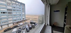 Blick vom Balkon auf einen Parkplatz mit einem Gebäude im Hintergrund.